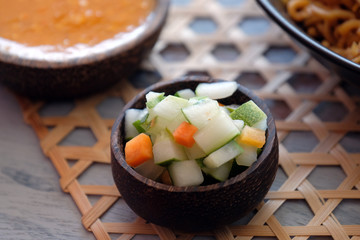 Traditional pickles from indonesia, cucumber and carrot in wooden little bowl.