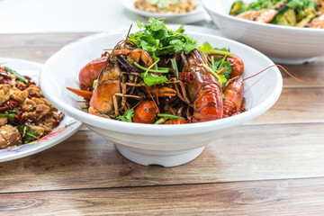 Chongqing Sichuan spicy dried chilli small lobsters, among other dishes in the background. Food photography at Chinese restaurant.