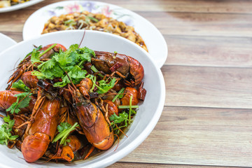 Chongqing Sichuan spicy dried chilli small lobsters, among other dishes in the background. Food photography at Chinese restaurant.