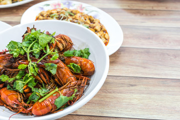 Chongqing Sichuan spicy dried chilli small lobsters, among other dishes in the background. Food photography at Chinese restaurant.