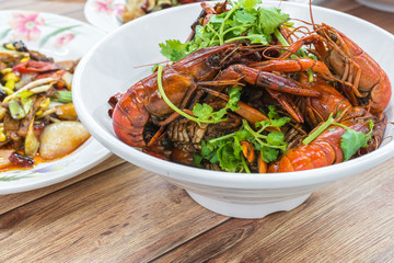 Chongqing Sichuan spicy dried chilli small lobsters, among other dishes in the background. Food photography at Chinese restaurant.