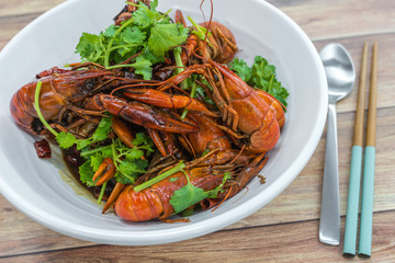 China, Chongqing Sichuan spicy dried chilli small lobsters, among other dishes in the background. Food photography at Chinese restaurant.