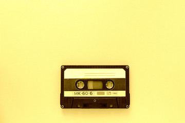 Old audio tape cassette, top view. Old technology concept. Yellow color toned