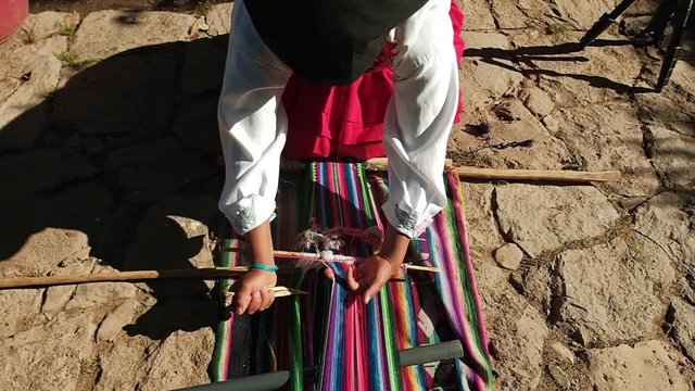 woman weaving a colorful loom