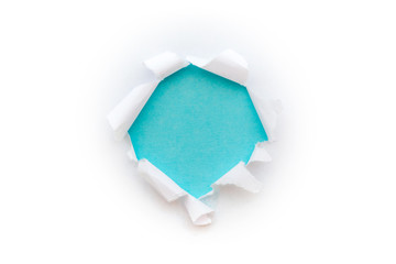 A round hole in white paper with torn edges isolated on a white background with a light blue color paper background inside. Good paper texture