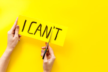 Motivation to be confident. Hands cut text I can't with scissors on yellow background copy space