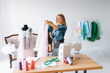 Working on new collection. New order. Female fashion designer works on the new clothes in the workshop.