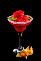 Closeup glass of red daiquiri strawberry cocktail decorated with mint and physalis isolated at black background.