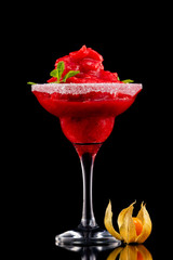 Closeup glass of red daiquiri strawberry cocktail decorated with mint and physalis isolated at black background.