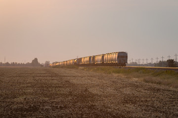 Fototapeta na wymiar Departing Train Under Golden Sunrise on the Prairie