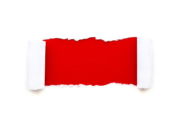 A hole in white paper with torn edges isolated on a white background with a bright red color paper...