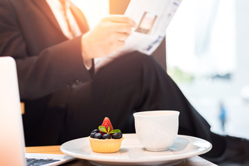 cup cake and coffee in dish and blur business man read newspaper