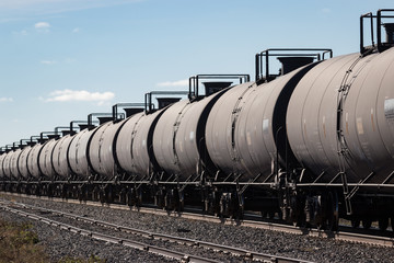 Naklejka premium Line of Black Tank Cars Under A Blue Sky