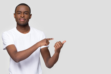 Handsome African American man pointing fingers aside at copy space