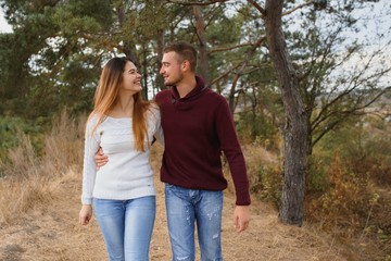 Couple in love lying on a picnic blanket in a park, enjoying beautiful autumn day in nature and cuddling