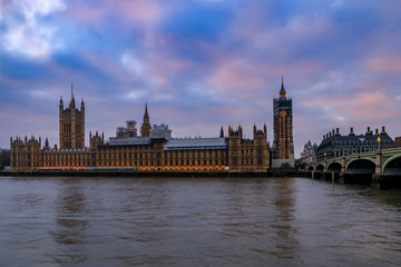 Obraz na płótnie Canvas Westminster Palace and Big Ben covered in scaffolding for restoration viewed across the Thames at sunset in London, UK