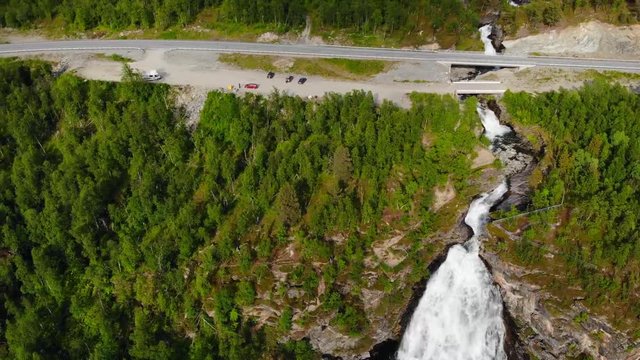 Aerial, pan, drone shot, of the Rovijokfossen waterfall, road Europavei and the Ivgojohka river, on a sunny, summer day, in Skibotndalen, in Storfjord, Norway