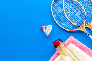 Tennis equipment - rockets, shuttlecock - on blue background top-down frame copy space