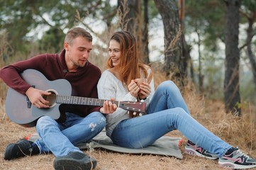 Couple in love lying on a picnic blanket in a park, enjoying beautiful autumn day in nature and cuddling