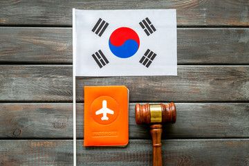 Visa to Korea concept. Korean flag near passport and judge hammer on dark wooden background top-down copy space