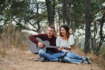 Couple in love lying on a picnic blanket in a park, enjoying beautiful autumn day in nature and cuddling