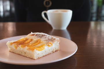 Delicious apricot dessert and coffee on cafe table. Close up