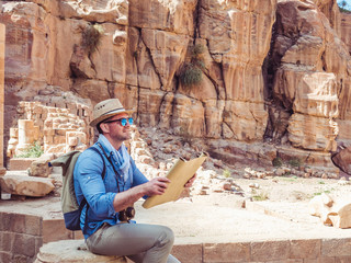Handsome man, exploring the sights of the ancient, fabulous city of Petra in Jordan. Colorful photos. Concept of leisure, vacation and travel