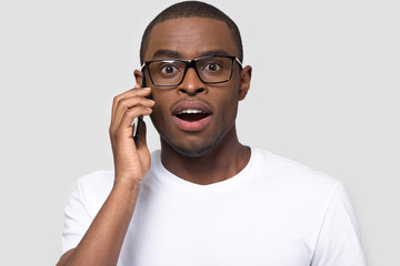 Surprised African American man hearing unexpected news by phone