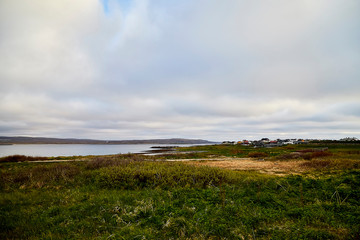 Varde, Norway - June 23, 2019: Calm landscape with water and fishing village on the bank of a beautiful fjord in a morning, Norway