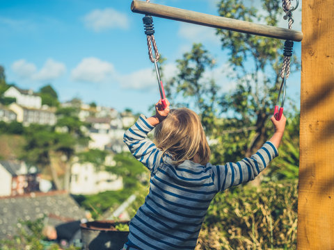 Toddler hanging from trapeze in garden