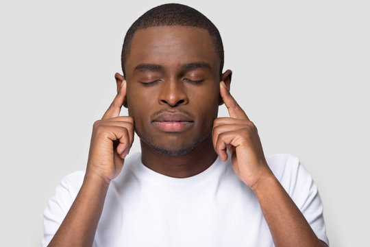 Calm African American man with closed eyes touching temples