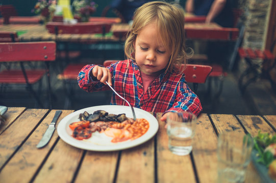 Toddler eating english breakfast in cafe