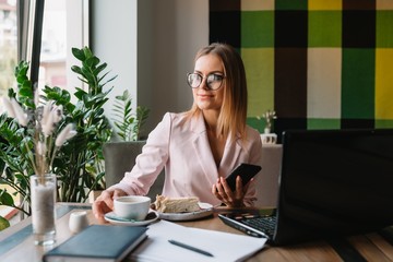 Portrait of young attractive businesswoman examining paperwork in bight light office interior sitting next to the window, business woman read some documents before meeting, filtered image