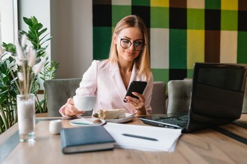 Business woman on the phone at office. Young business woman having phone call at the office. Smiling business woman. Pretty young business using smartphone at the loft office.