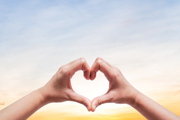 Woman hold hands up to sky in the shape of love heart on nature sun light flare and cloud with sky background.Valentine's day,Sign of Love,Hand gesture Concept.Copy space empty blank.                