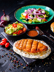 grilled chicken fillet with fresh salad on a dark background