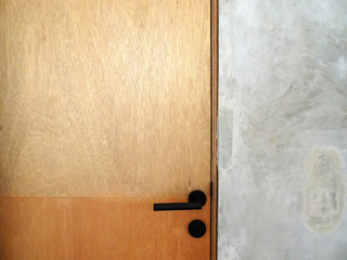 Wood multiplex door with black door handle and cement finishing wall
