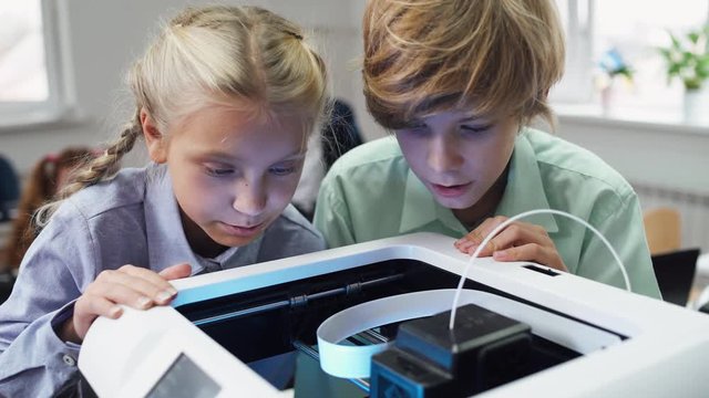 Education in the modern school, children learn modeling, boy and girl watching of process 3D printer prints.