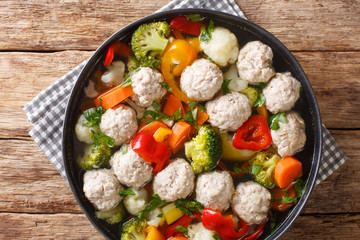 Homemade soup with meatballs, broccoli, pepper, cauliflower, potatoes and carrots close-up in a plate. Horizontal top view