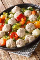 Vegetable soup with chicken meatballs close-up in a plate on the table. vertical