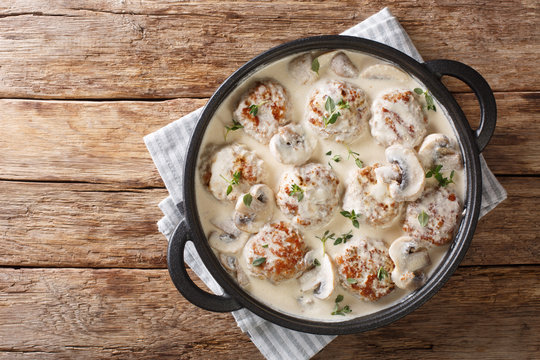 Main dish of meatballs with mushrooms served in creamy cheese sauce with thyme close-up in a pan. horizontal top view