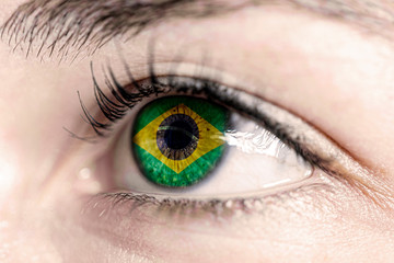 Fototapeta premium Flag of Brazil reflects in woman green eye - close-up view - election, sport, hope, young, generation 