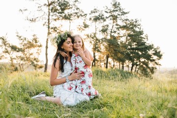 Stylish mother and handsome daughter having fun on the nature. Happy family concept. Beauty nature scene with family outdoor lifestyle. family resting together. Happiness in family life. Mothers day