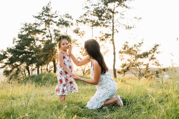 Fototapeta premium Mother and daughter having fun in the park. Happiness and harmony in family life. Beauty nature scene with family outdoor lifestyle.
