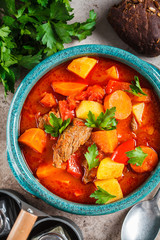 Traditional hungarian goulash. Beef stew with potatoes, carrots and paprika in blue dish, top view.
