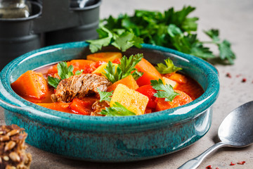Traditional hungarian goulash. Beef stew with potatoes, carrots and paprika in blue dish.