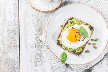Sandwich with avocado, egg and spinach on white wooden background. Healthy diet breakfast