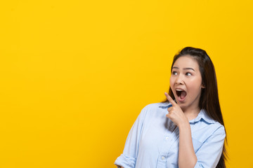 Fototapeta premium Shock asian young woman pointing finger up with surprise facial expression.