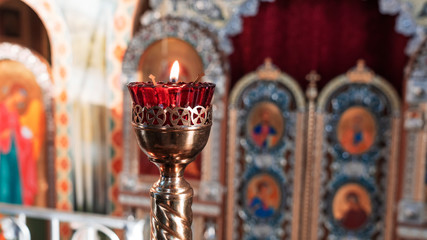 Orthodox Church Lamp with lit Candle and Red Glass on the icon background.