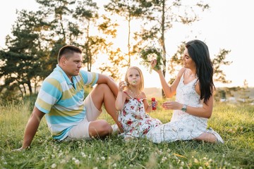 happy family concept - father, mother and child daughter having fun and playing in nature.